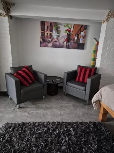 ein Wohnzimmer mit zwei Stühlen und einem Tisch in der Unterkunft Secret Bunker at Vikings Forge in Bury Saint Edmunds