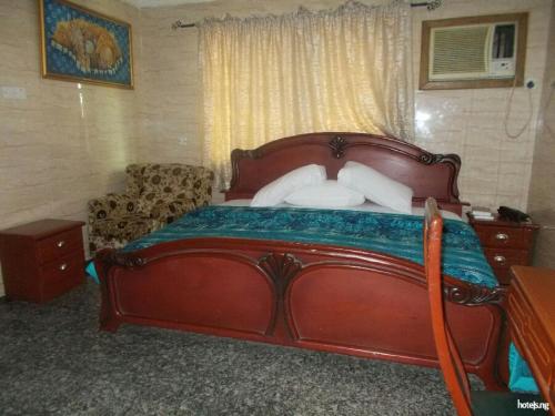 a bedroom with a large wooden bed and a couch at Cynergy Suites Festac Town - Standard in Amuwo