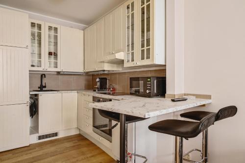 eine Küche mit weißen Schränken und 2 Barhockern in der Unterkunft Leiligheter i sentralt Bergenshus in Bergen