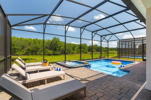 une piscine dans un igloo de verre avec des bancs et une table de billard dans l'établissement Great 8 br villa w games theater pool by Disney, à Kissimmee