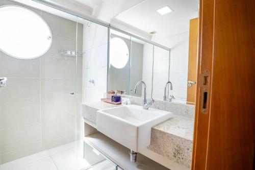 a white bathroom with a sink and a mirror at Point Convenience by Marzani Host in Goiânia