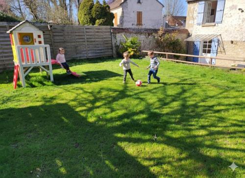 three children playing with a soccer ball in a yard at Maison authentique du Vexin in Théméricourt