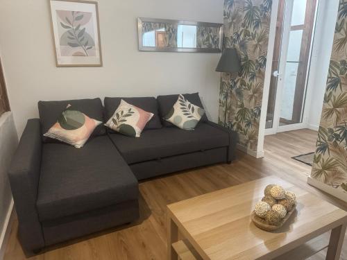 a living room with a black couch and a table at Casita La Mercería in Güimar