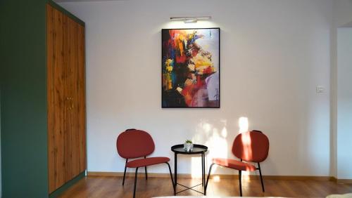 2 sillas y una mesa en una habitación con una pintura en Meet Prishtina Apartment, en Pristina