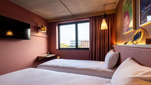 a hotel room with two beds and a window at greet Hotel Reims Tinqueux in Reims