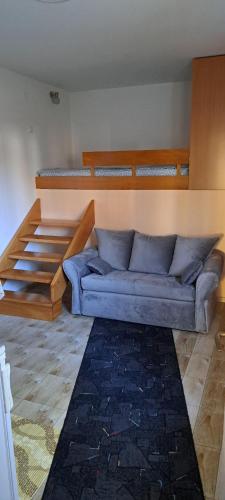 un canapé bleu dans une chambre avec deux lits superposés dans l'établissement Marija apartmani, à Kraljevo