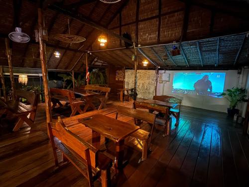 a restaurant with wooden tables and a large screen at Vanara Bungalows in Ko Chang