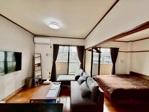 a living room with a bed and a couch at Stay Plus Azunoa in Oyama