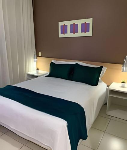 a bedroom with a large white bed with blue pillows at Luxuoso Flat no Aldeia das Águas Com Vista para Piscina in Volta Redonda