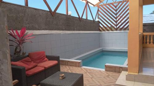 a pool on the roof of a building with a couch and a chair at Océan Voyages Mitsamihouli in Mitsamiouli