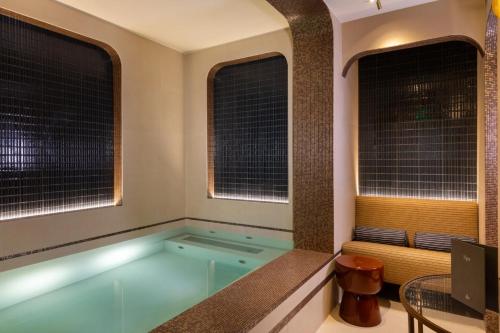 a hot tub in a room with windows at Hôtel Louvre Piemont & Spa in Paris