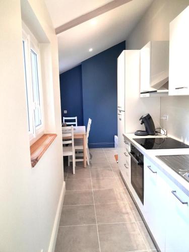 a kitchen with white cabinets and a dining room with a table at Appartement Hyper centre refait à neuf in Luchon