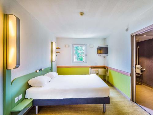 a room with a bed with white sheets and a window at Ibis Budget Chalon Sur Saone Nord in Chalon-sur-Saône