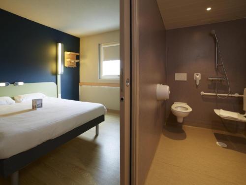 a hotel room with a bed and a toilet at Ibis Budget Chalon Sur Saone Nord in Chalon-sur-Saône