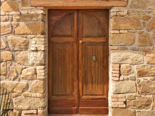 una puerta de madera marrón en un edificio de piedra en Nucidda - Country House with sea & mountain views, en Reitano