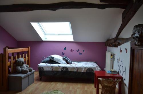 a bedroom with a bed with purple walls and a skylight at Gîte la Framboisine in Bourgvilain