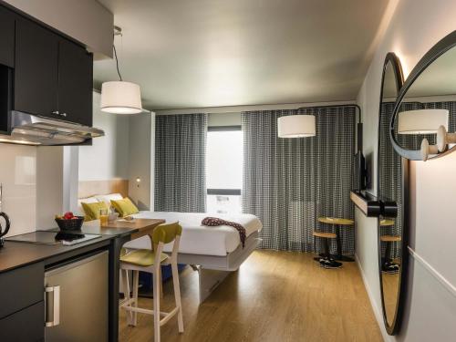 ein Hotelzimmer mit einem Bett und einem Tisch sowie einer Küche in der Unterkunft Aparthotel Adagio access Colombes La Défense in Colombes