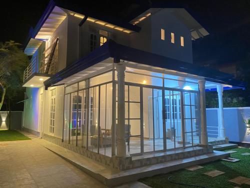 a house with a lit up front porch at night at White N Villa in Wadduwa