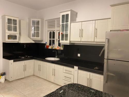 a kitchen with white cabinets and a sink and a refrigerator at White N Villa in Wadduwa