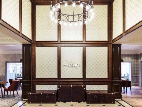 a lobby with a chandelier and some tables and chairs at Mercure Haydock Hotel in Haydock