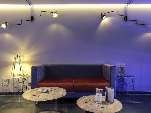 Una sala de estar con un sofá y dos mesas. en Mercure Paris Malakoff Parc des Expositions, en Malakoff