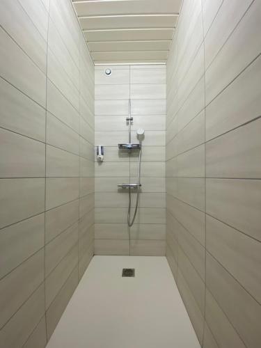 a bathroom with a shower with white tile walls at L'Oustal Des Dômes in Orcines
