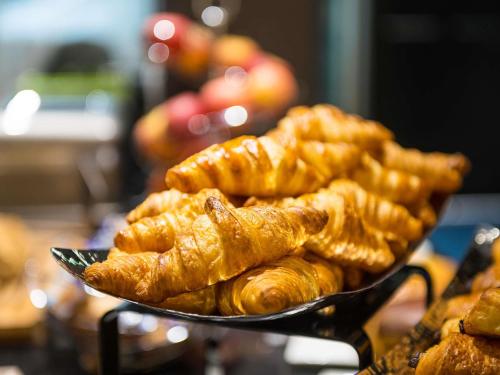 un plato de cruasanes y otros pasteles en una mesa en ibis Styles Deauville Centre, en Deauville