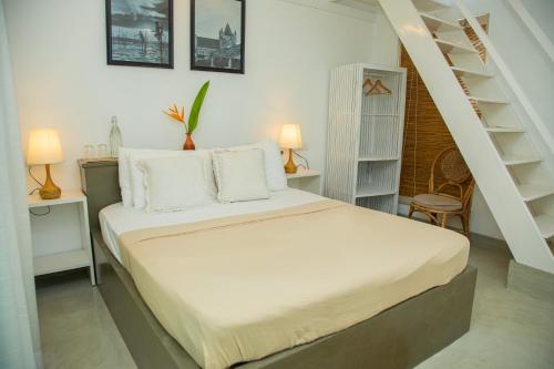 1 dormitorio con cama con sábanas blancas y escalera en Water's Edge Villa Ahangama, en Ahangama
