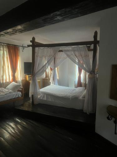 a bedroom with a canopy bed with white sheets at Castel Templul Cavalerilor in Vălişoara
