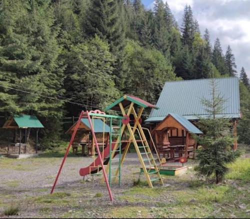 a playground with a slide in front of a cabin at Лісова тиша Сімейні номера in Synevyrsʼka Polyana