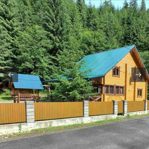 a wooden house with a fence next to a forest at Лісова тиша Сімейні номера in Synevyrsʼka Polyana
