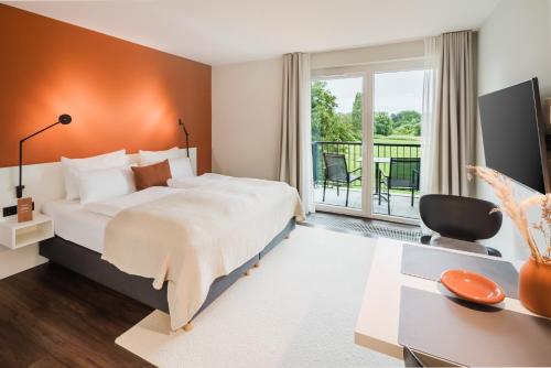 a bedroom with a large bed and a balcony at Überwasser Hotel in Cuxhaven