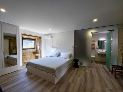 a bedroom with a bed and a bathroom with a sink at SOUTELO House in Grovelas