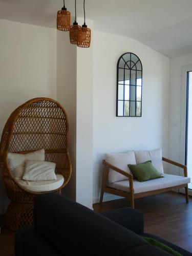 a living room with a wicker chair and a couch at Loc' Maria - Grands Sables in Groix