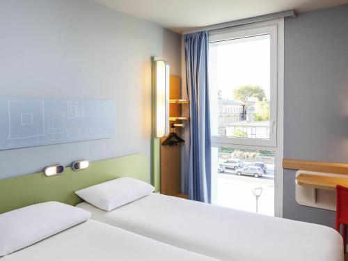 a hotel room with two beds and a window at Ibis Budget Mulhouse Centre Gare in Mulhouse