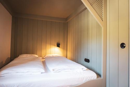 a bed with white sheets and a light on it at STUBN in der Frasdorfer Hütte in Frasdorf