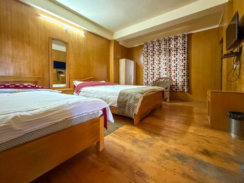 a hotel room with two beds and a window at JD House in Tawang
