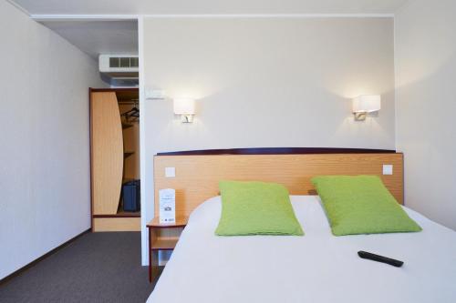 Un dormitorio con una gran cama blanca con almohadas verdes. en Campanile Lille - Lomme, en Lomme