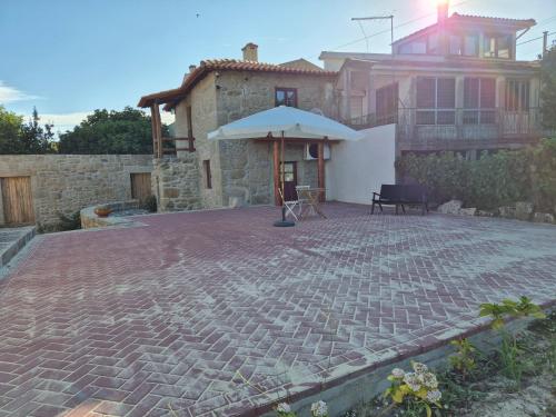 une terrasse avec un parasol en face d'une maison dans l'établissement Charming Douro Valley Stone Home, à Coura