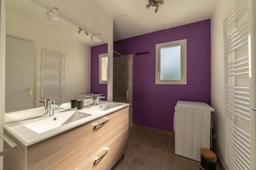 La salle de bains est pourvue d'un lavabo et d'un mur violet. dans l'établissement Gite Les Bouches Rouges, à Vesseaux