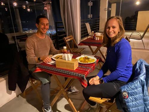 a man and woman sitting at a table with a plate of food at Panorama Guest House Jabal Shams in Sa‘ab Banī Khamīs