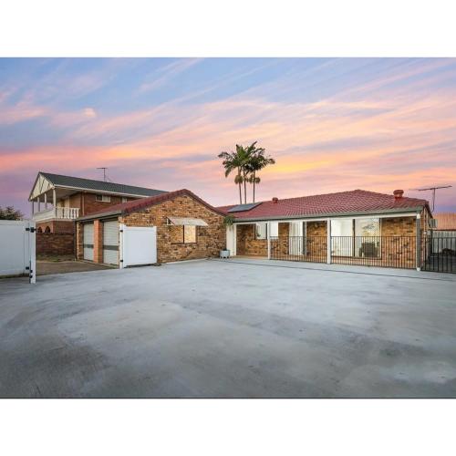 a house with a parking lot with a palm tree at Spacious Family Retreat in Perfect Location! in Brisbane