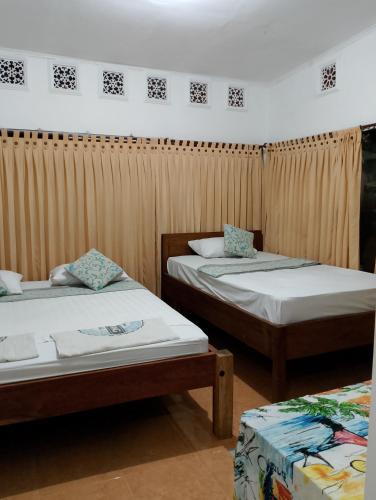 two beds in a room with curtains at fulles guest house in Gili Trawangan