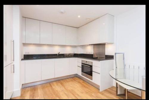 a kitchen with white cabinets and a glass table at luxurious Room with City Views in Woolwich