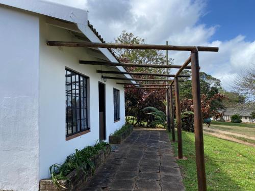 a pergola on the side of a white house at Luxury modern farm cottage with sea view in Southbroom