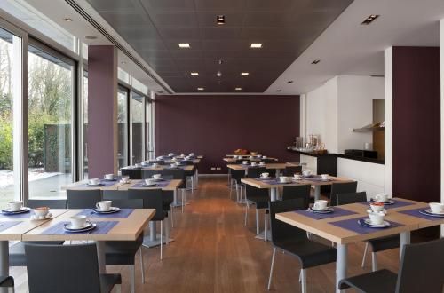 a dining room with tables and chairs and windows at Parkhotel Izegem in Izegem