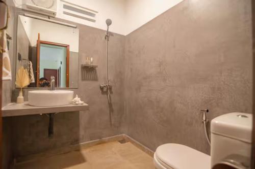 a bathroom with a sink and a toilet and a mirror at A peaceful villa for recuperation in Ahangama