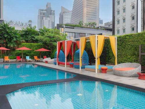a pool with colorful umbrellas and chairs next to a building at Mercure Bangkok Sukhumvit 11 in Bangkok