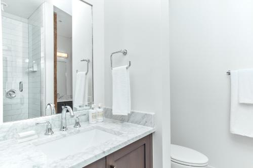 a white bathroom with a sink and a toilet at The Luzianne in New Orleans