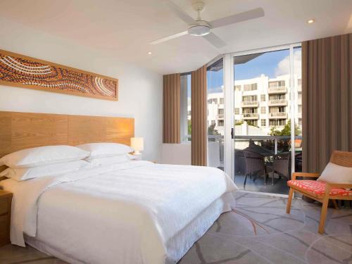 une chambre avec un grand lit blanc et un balcon dans l'établissement Sofitel Noosa Pacific Resort, à Noosa Heads